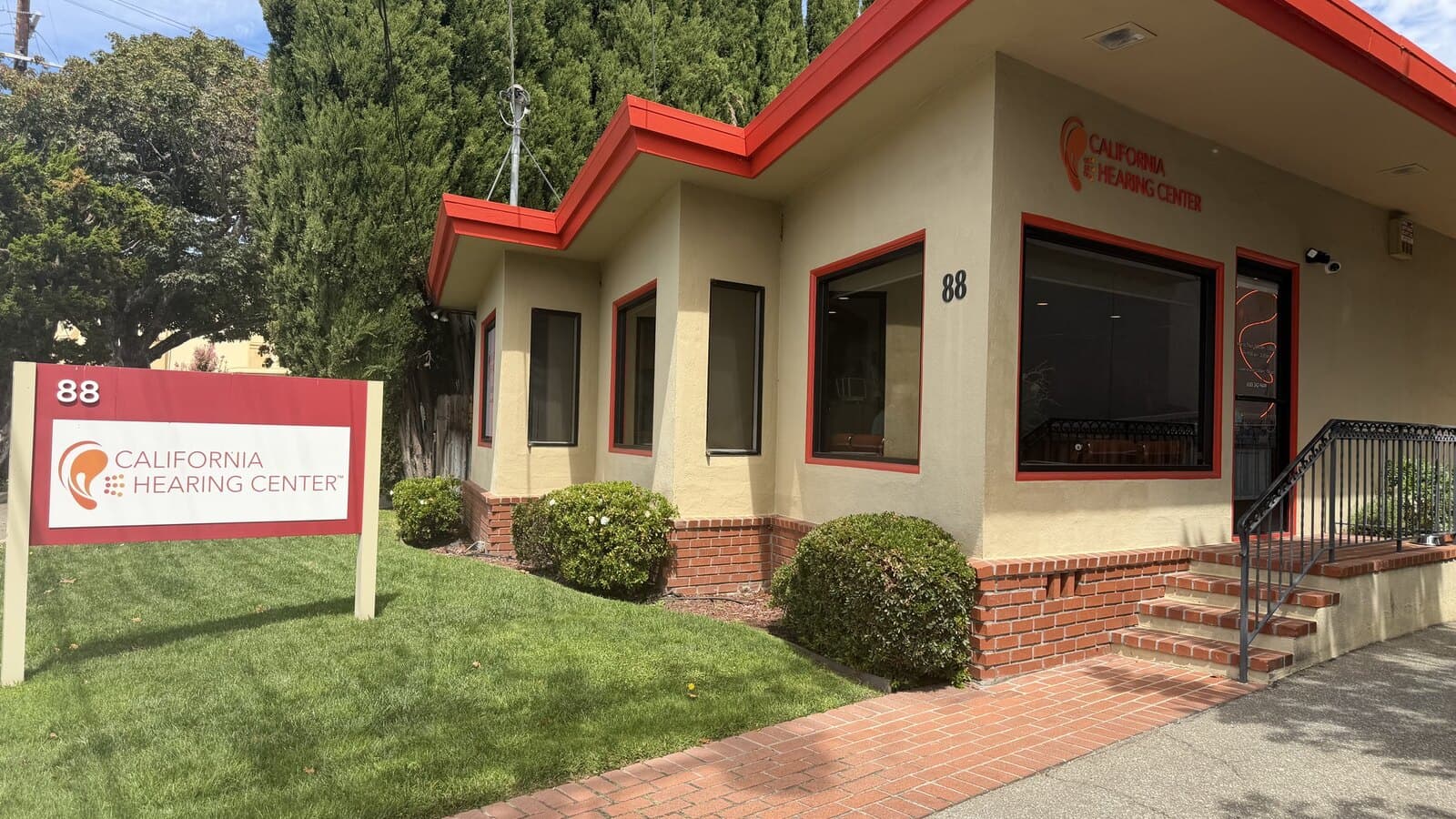 The California Hearing Center office at 88 N. San Mateo Drive: a single-storey building with a red roofline, and a red-and-white sign on the lawn at the sidewalk.