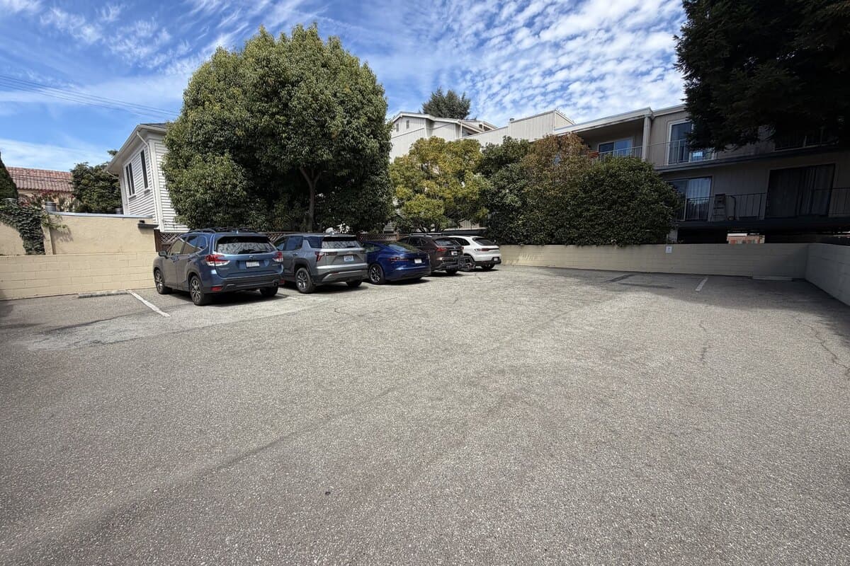 An open parking lot behind the office building with marked spaces and a few parked cars.